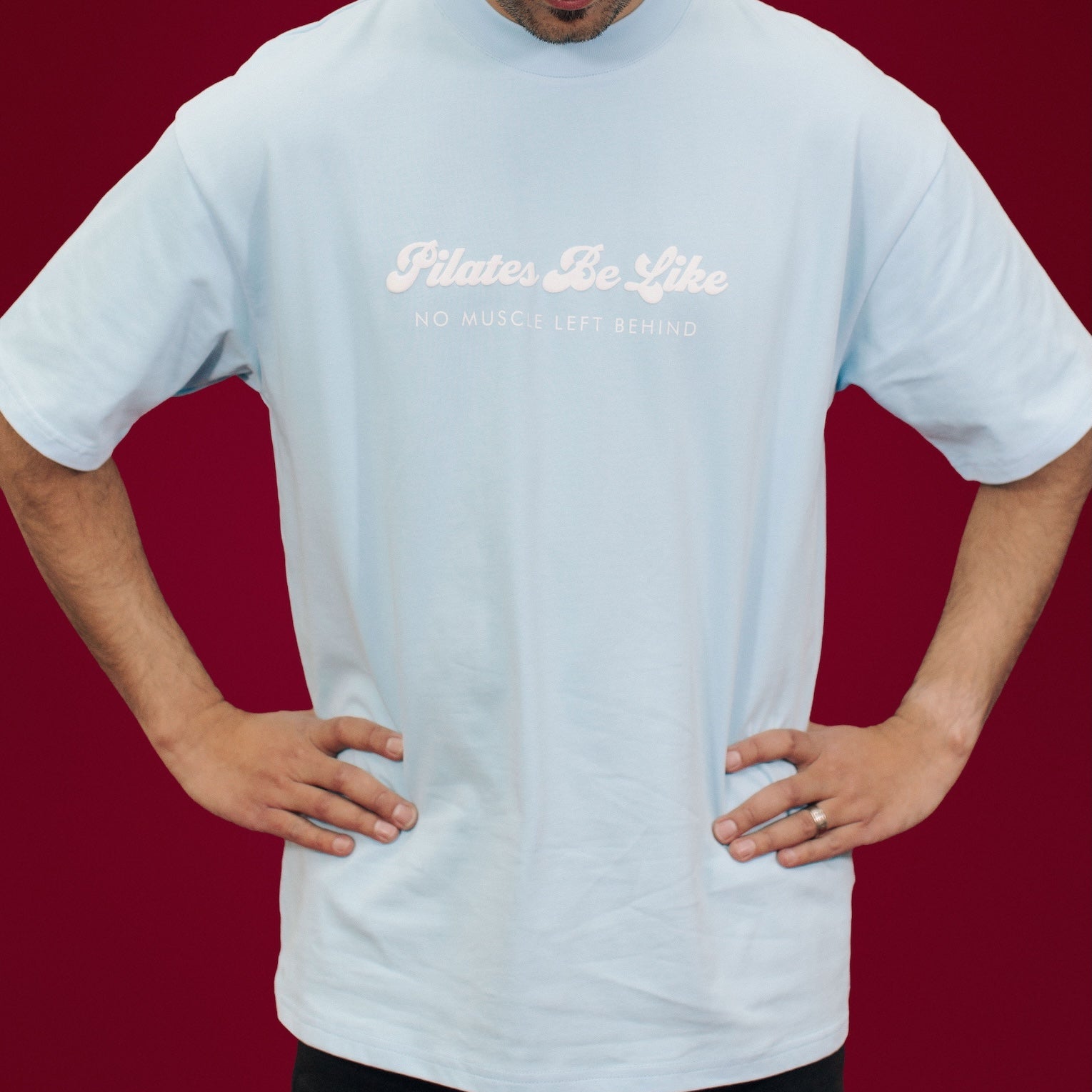 Person wearing a light blue t-shirt with text and a pink cap on a red background