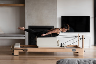 The Studio Pilates Reformer - Action Shot with Woman Exercising | Your Reformer