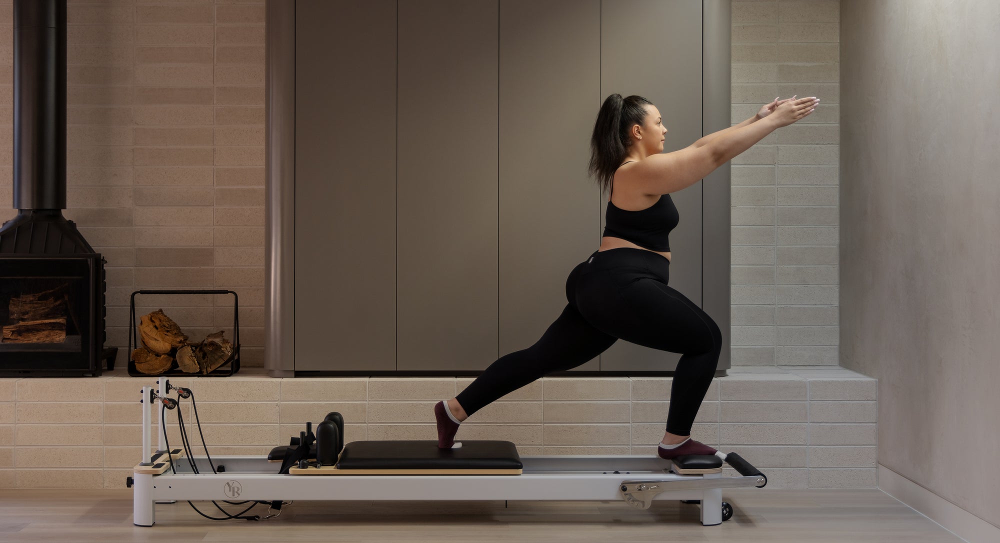 Woman standing on pilates reformer in her home