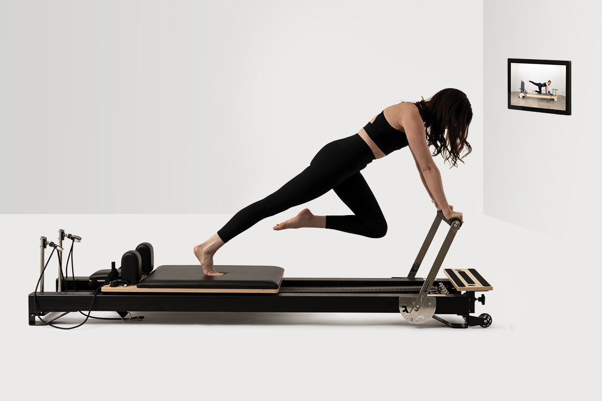 Woman using pilates reformer maching and kiosk
